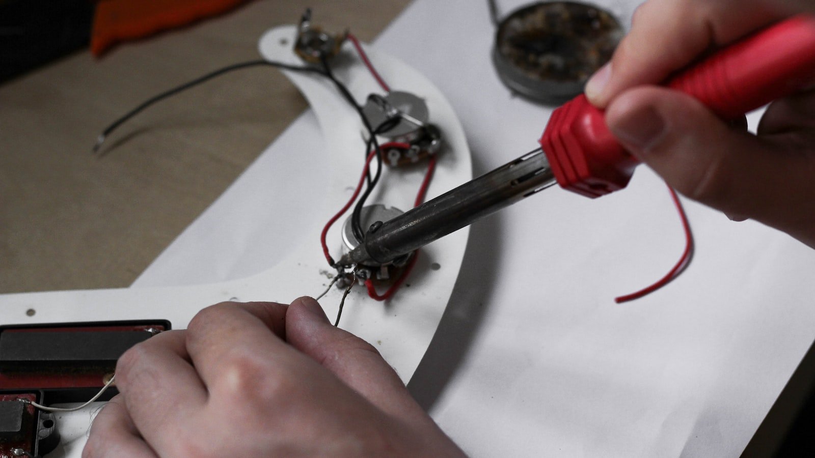 Hands soldering electronics wiring at an assembly bench