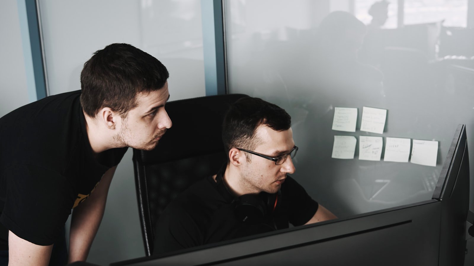 Two software developers reviewing code together at a monitor