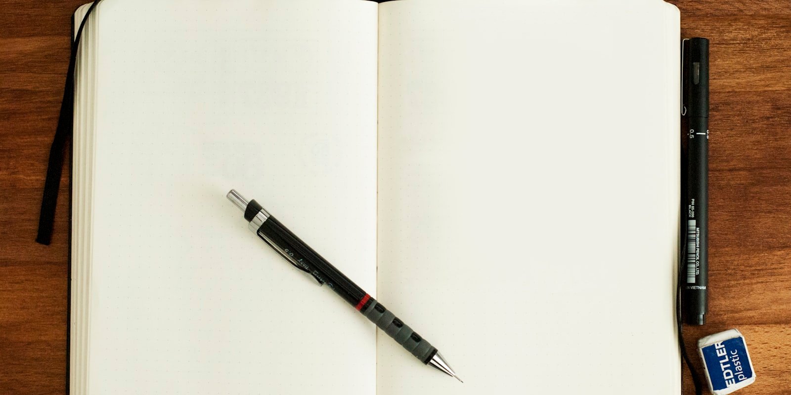 Open engineering notebook with mechanical pencil on a wooden desk