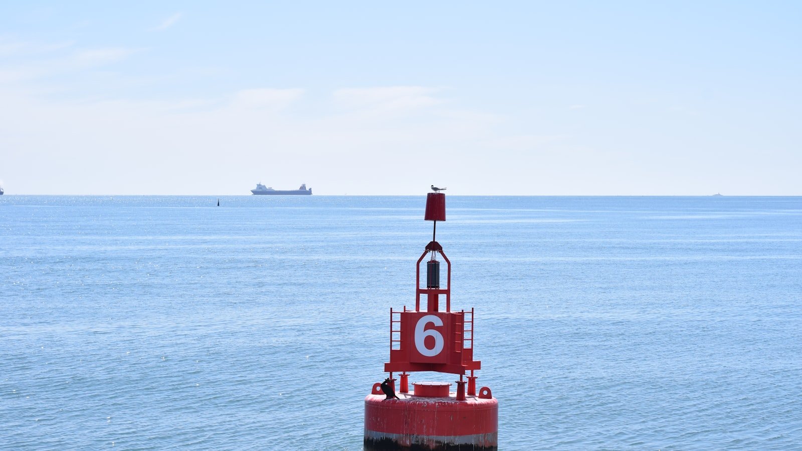 Red navigation buoy floating on a calm blue sea